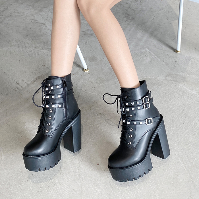 Bottines gothiques noires en cuir avec talons épais et clous carrés, vue latérale sur sol gris