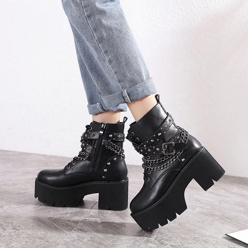 Chaussures femmes gothiques à pointes courtes Rebelstrike noires en cuir avec chaînes et clous, plateforme épaisse et talon carré, portées avec jean retroussé