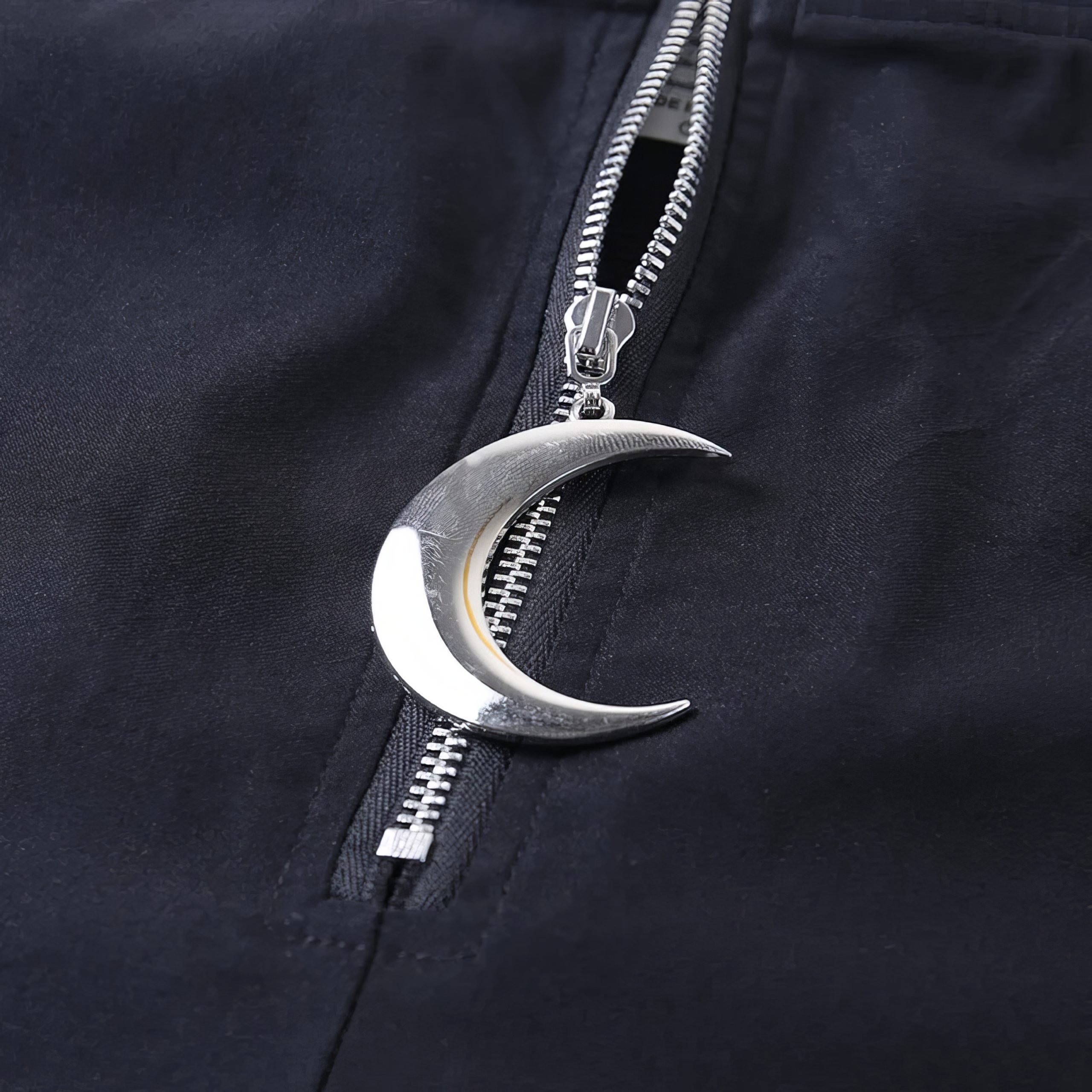 Détail du pantalon noir gothique MysticMoon avec fermeture éclair argentée ornée d'un pendentif lune