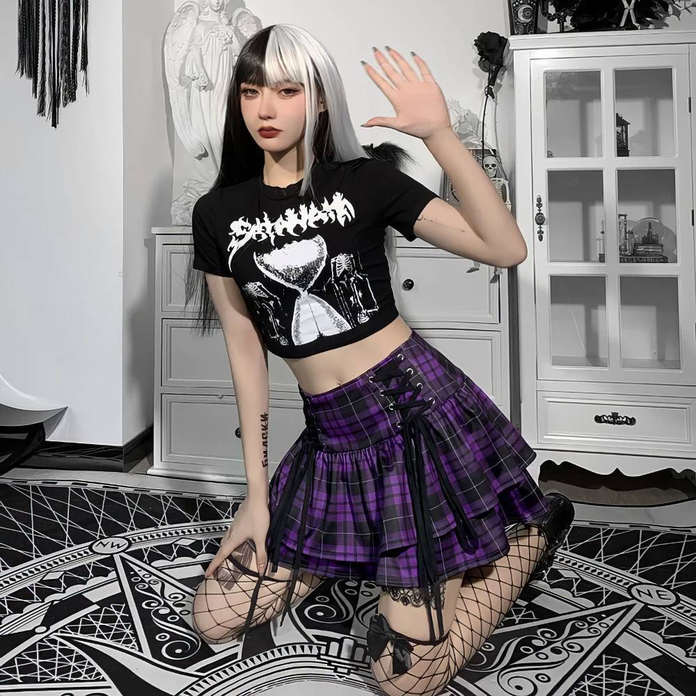 Jupe écossaise gothique Lunaria en tissu violet à carreaux noirs avec volants superposés et détails lacés, portée avec un t-shirt noir imprimé et des résilles noires