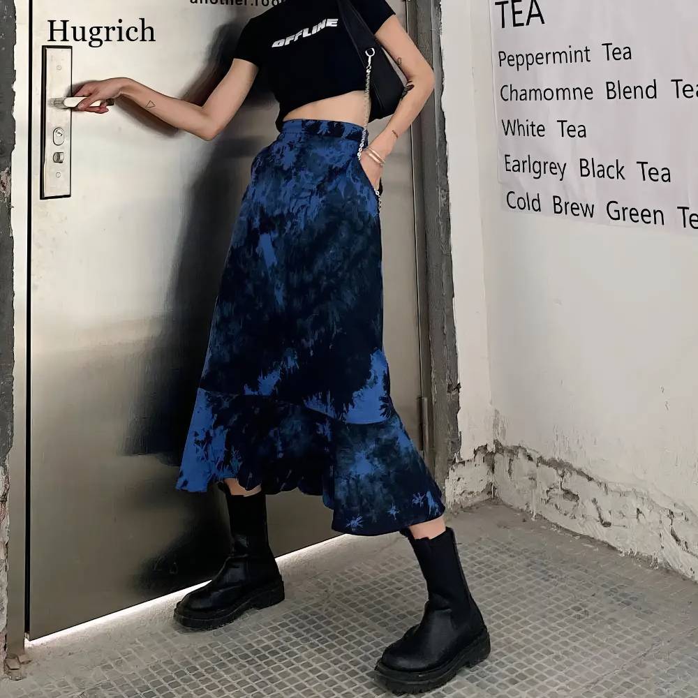Jupe gothique noir et bleu Ebonflameia en tissu fluide avec motif tie and dye, coupe longue asymétrique avec volant en bas, portée avec bottines noires