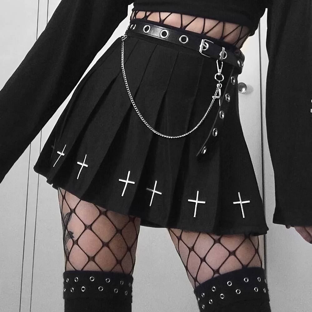 Jupe noire gothique plissée avec croix blanches brodées en bas, ceinture à œillets et chaîne argentée, portée avec résille et manches longues noires