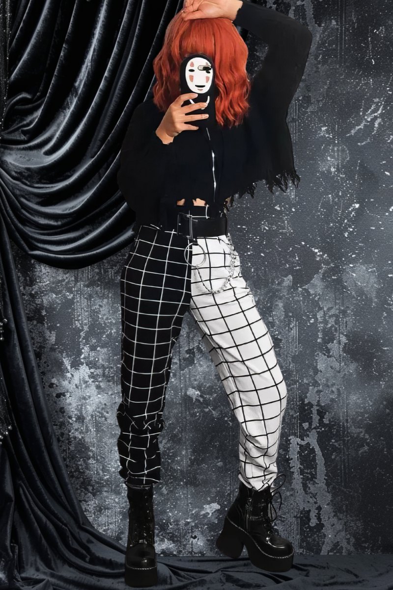 Pantalon gothique femme noir et blanc avec motif à carreaux, modèle DarkWhiteWave, coupe droite, porté avec bottines noires et pull noir à imprimé visage