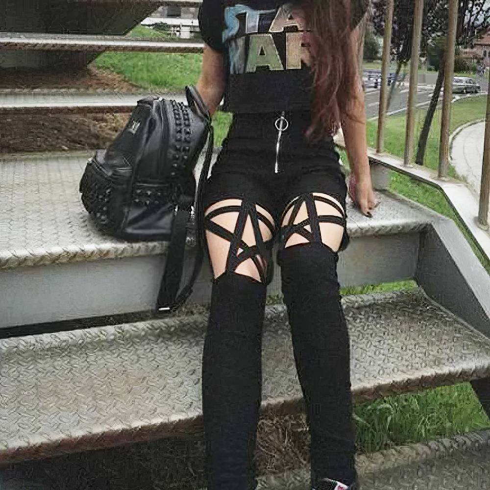 Pantalon gothique noir Victorium avec motif pentagramme en lanières sur les cuisses, porté assis sur des marches métalliques