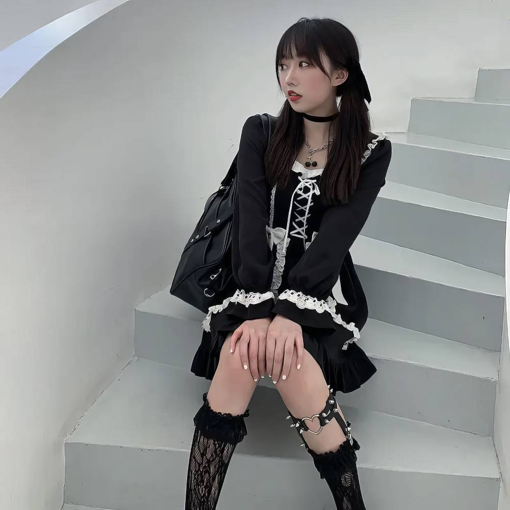 Robe gothique lolita noire en velours avec dentelle blanche, manches longues bouffantes, corset lacé et jupe plissée, modèle SinisterSymphony, vue assise de face