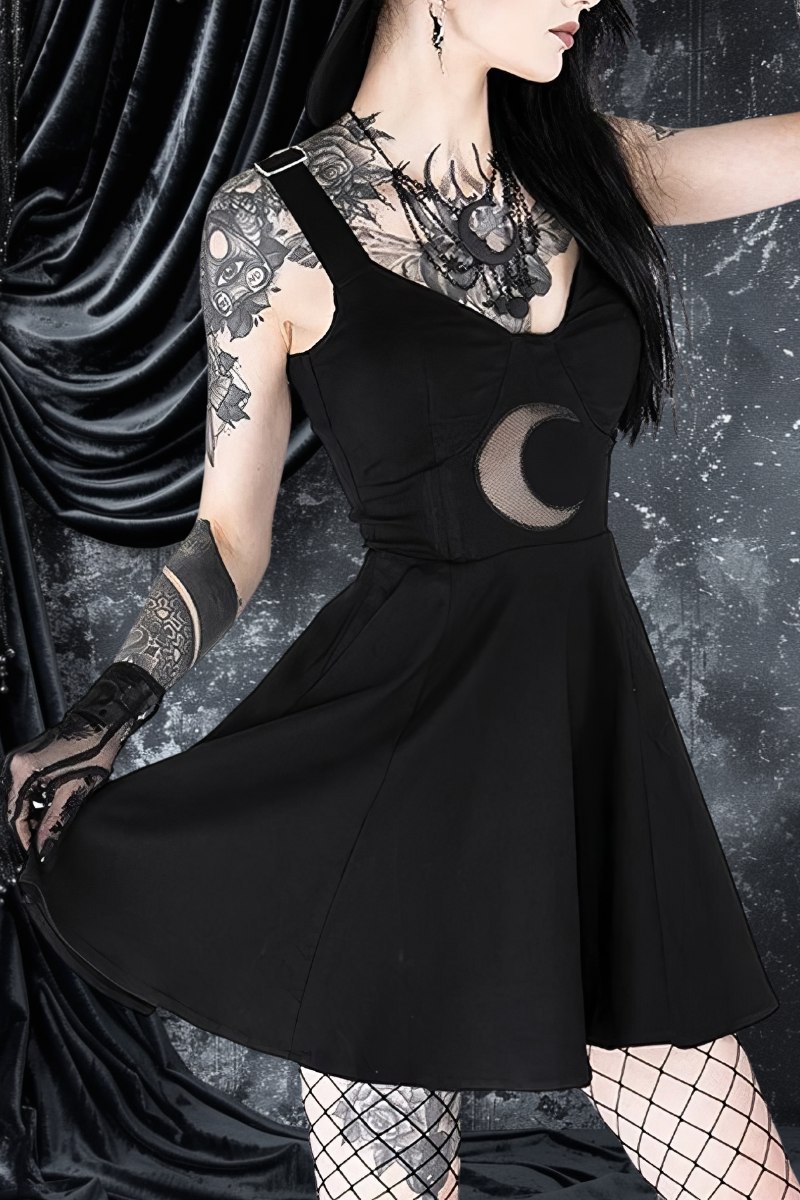 Robe gothique noire en tissu uni avec motif lune découpée sur la taille, portée par un mannequin avec tatouages et collants résille