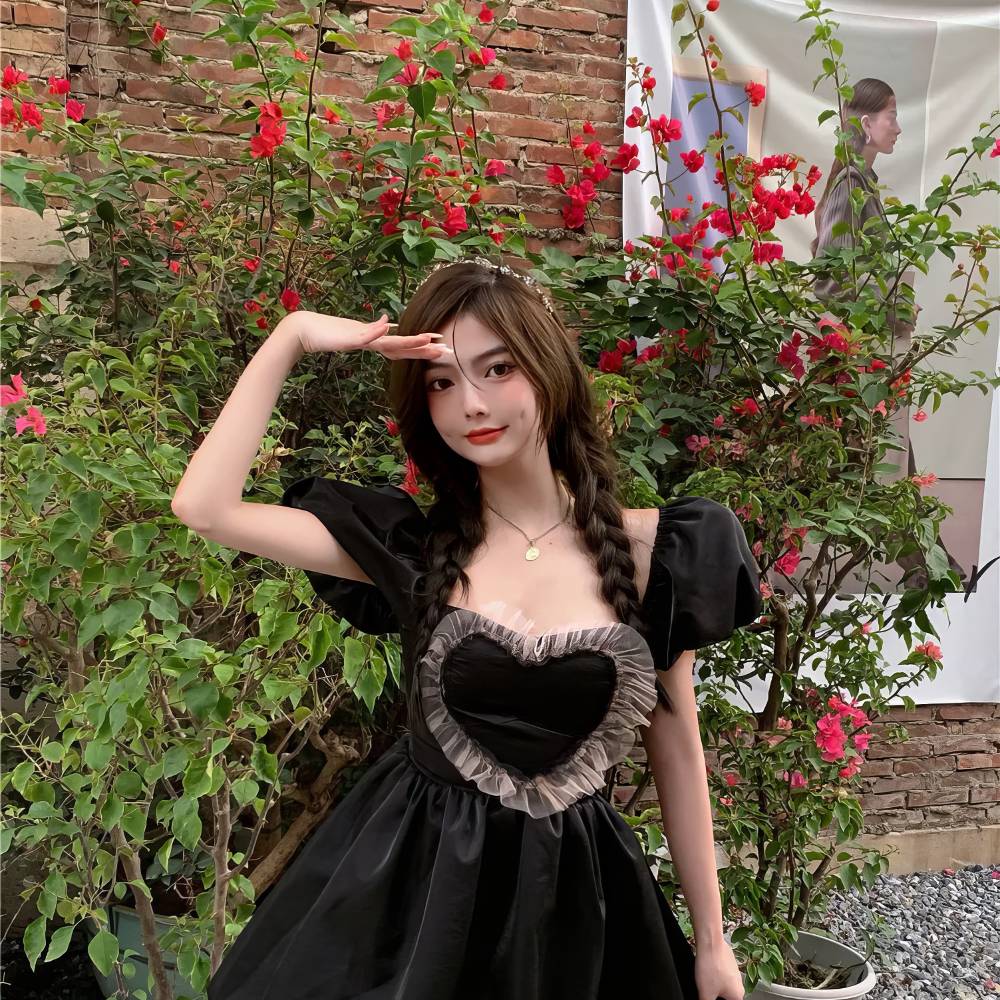 Robe gothique romantique courte noire en velours avec corsage en forme de cœur et manches bouffantes, modèle RebelRequiem, vue de face en extérieur