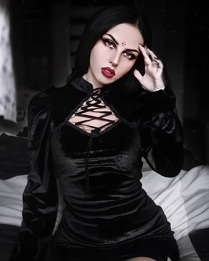 Robe gothique élégante en velours noir avec laçage croisé sur le décolleté portée par un modèle dans une ambiance sombre