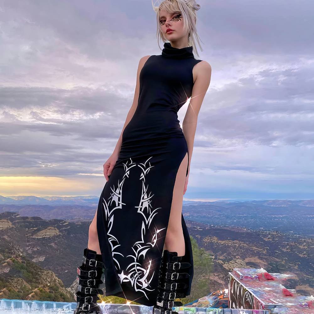 Robe longue gothique romantique noire avec col montant et motifs barbelés blancs, fentes latérales, portée avec bottes noires à boucles