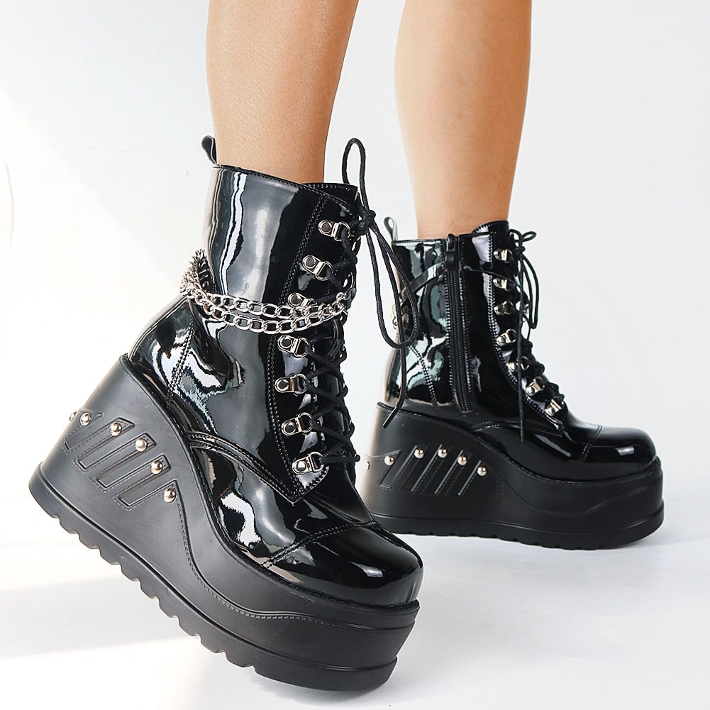 Bottes gothiques noires brillantes en cuir verni avec plateforme épaisse, lacets avant, chaîne argentée décorative et clous métalliques sur la semelle