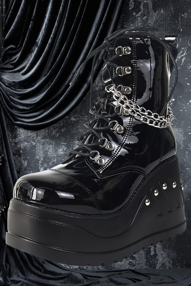 Bottes gothiques noires brillantes en cuir verni avec plateforme épaisse, lacets, chaînes argentées et clous décoratifs sur le talon