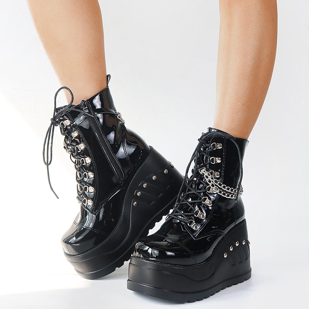 Bottes gothiques noires brillantes en cuir verni avec plateforme épaisse, lacets croisés et chaînes argentées décoratives, vue latérale sur les deux pieds