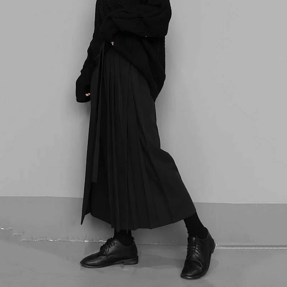 Pantalon jupe gothique femme noir en tissu plissé porté de profil avec chaussures noires