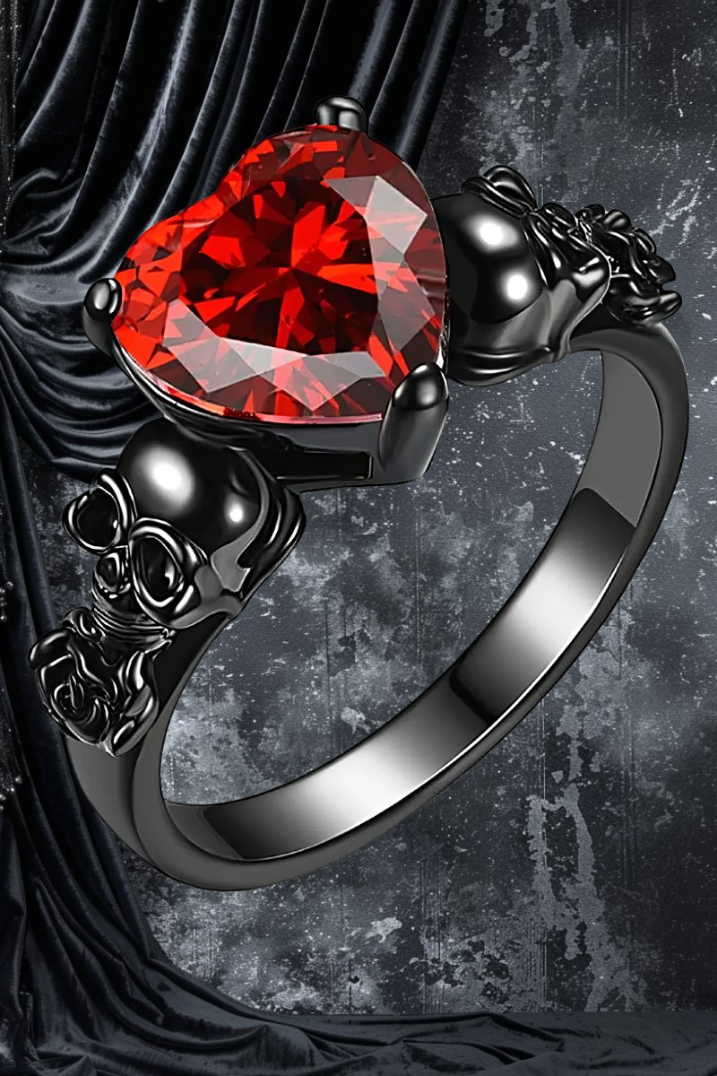 Bague de fiançailles gothique avec cœur rouge en pierre taillée, monture noire ornée de motifs crânes et décorations baroques