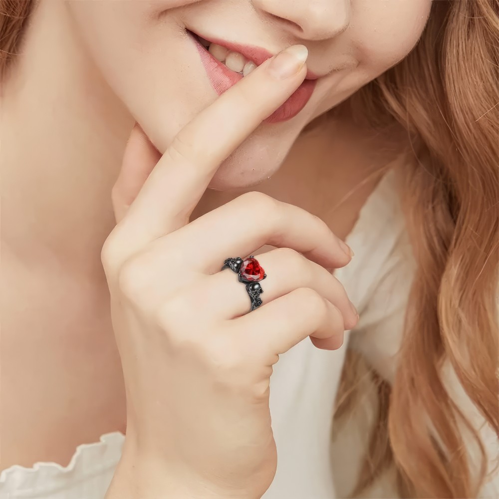 Bague de fiançailles gothique cœur rouge Shadowred portée sur le doigt, détail du motif cœur rouge sur monture noire