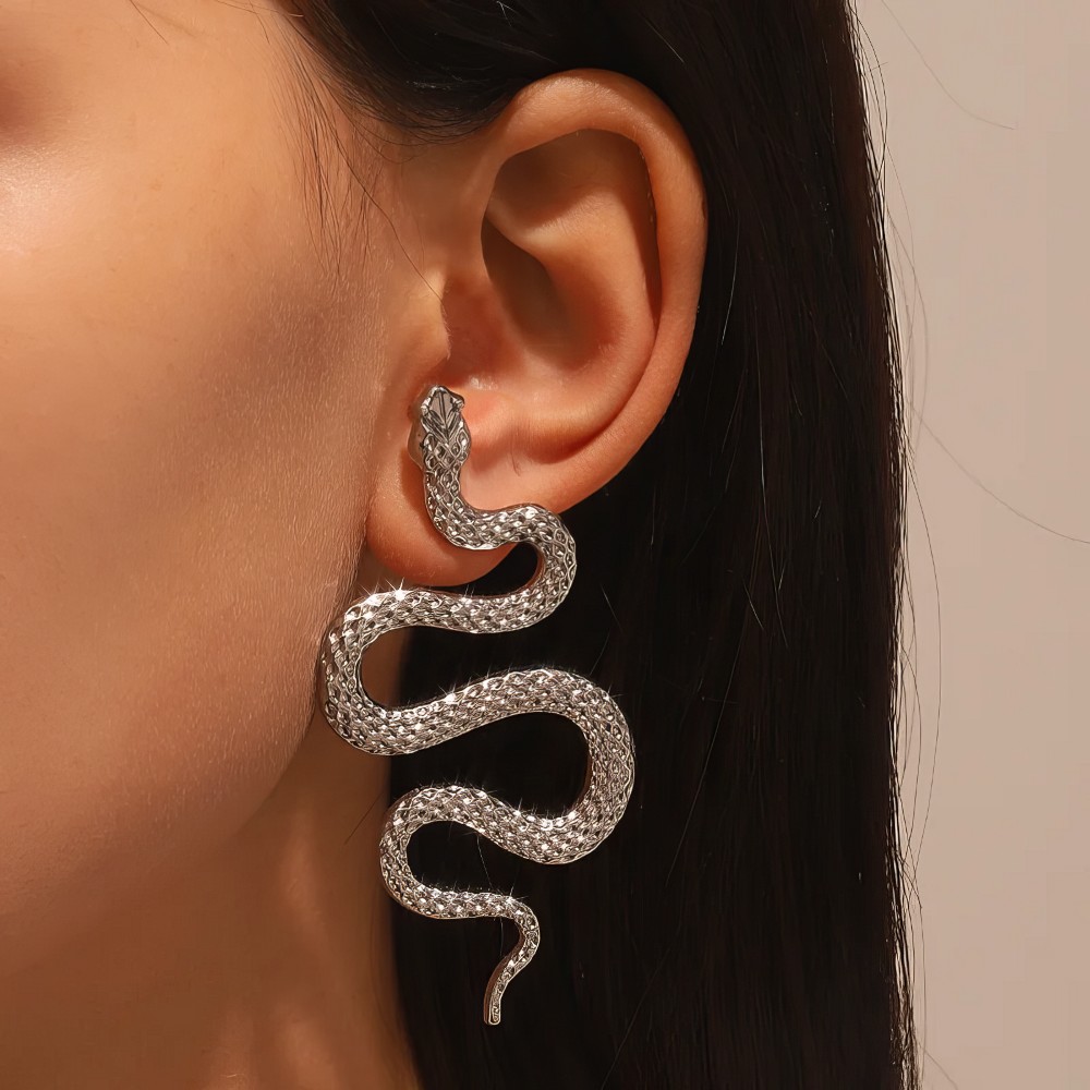 Boucle d'oreille gothique serpent en S argentée portée, détail de la texture écaille métallique