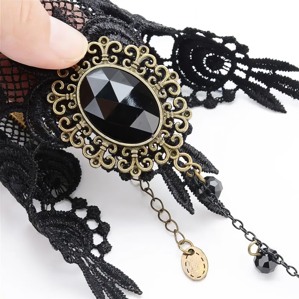 Bracelet bague gothique noire MystikClasp en dentelle noire avec pierre noire facettée ovale et décor baroque doré, détail chaîne fine avec pendentif rond