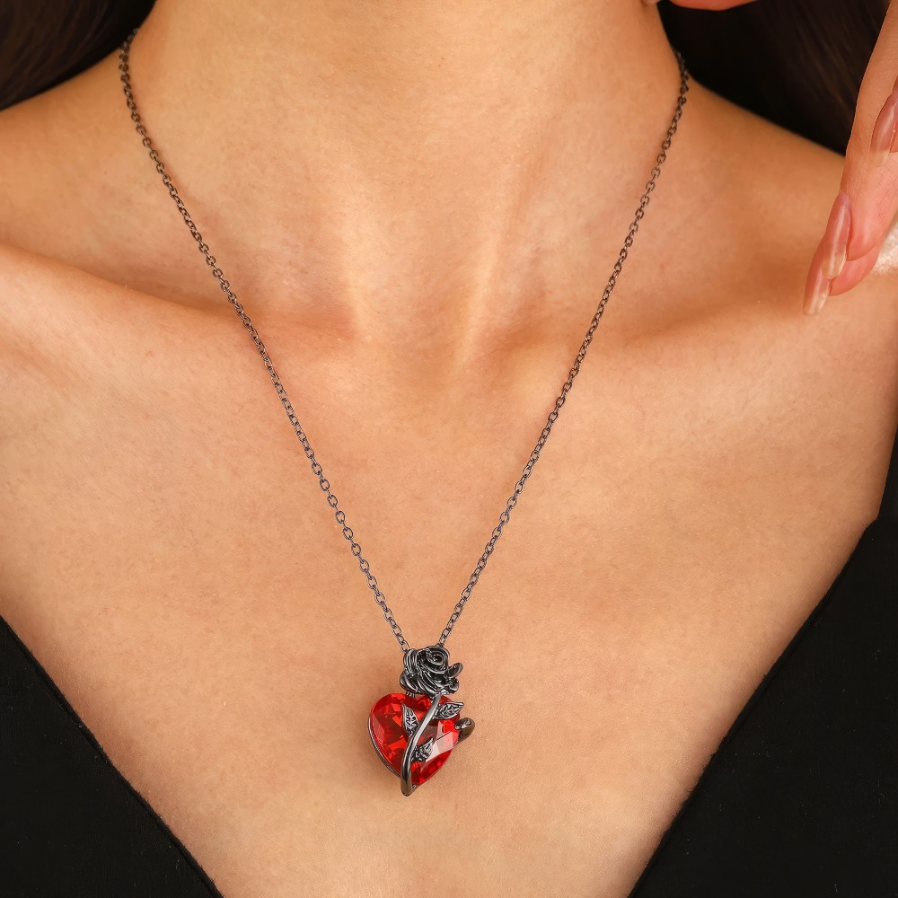 Collier gothique Cryptia avec pendentif cœur rouge en métal noir porté autour du cou, détail chaîne fine et pendentif sculpté