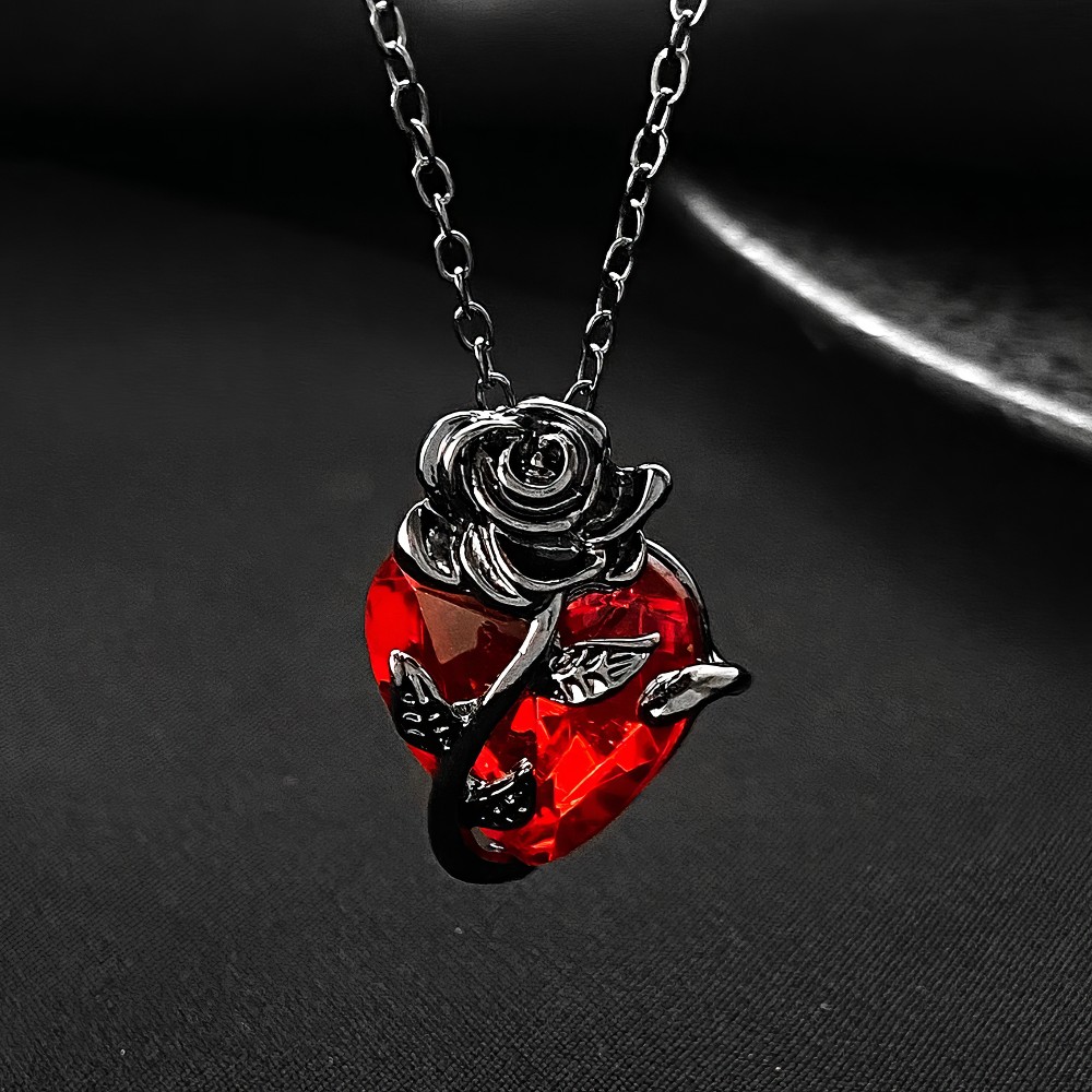 Collier gothique cœur rouge en métal argenté avec rose et épines, pendentif détail sur fond noir