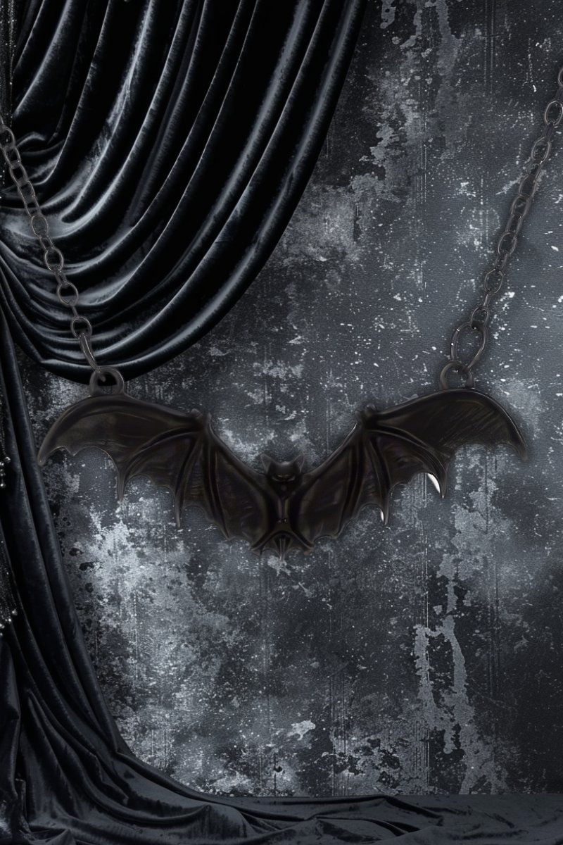 Collier gothique Villa Diodati en métal noir avec pendentif ailes de chauve-souris déployées sur fond texturé sombre et drapé en velours noir